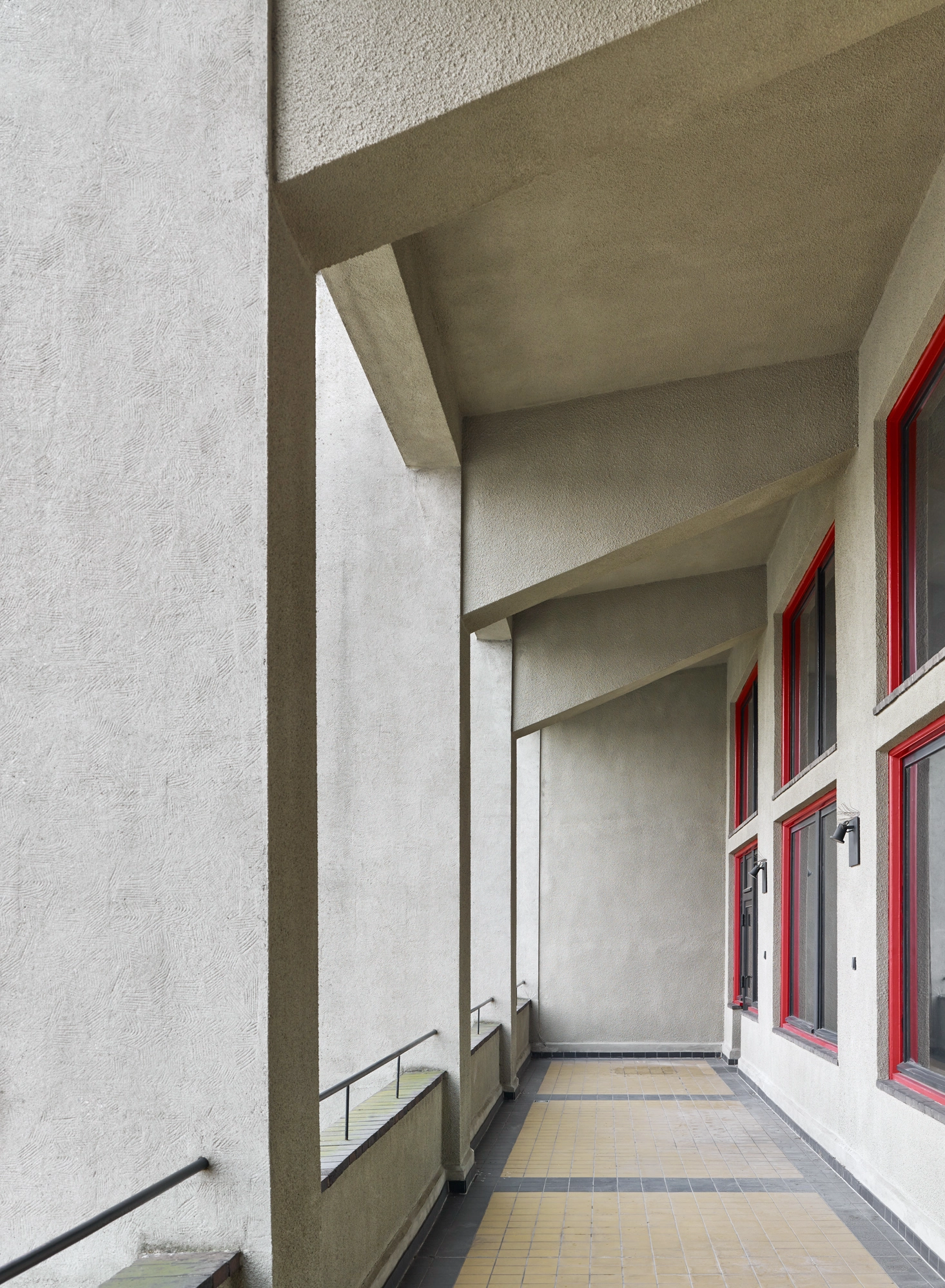 Außenflur mit roten Fensterrahmen und Sichtbeton im Haus der Buchdrucker Berlin